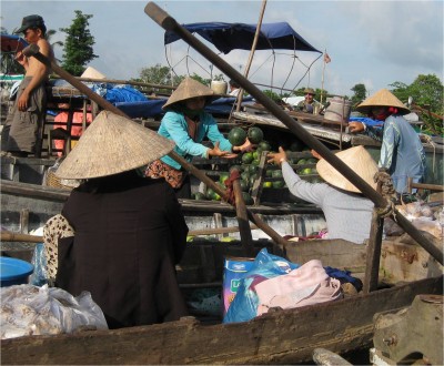 Two women completing a "Money for Melons" transaction, unsubsidized by the Vietnamese government, that will inevitably stimulate the local economy and environment through job growth and carbon offsets by increasing melon production. 
